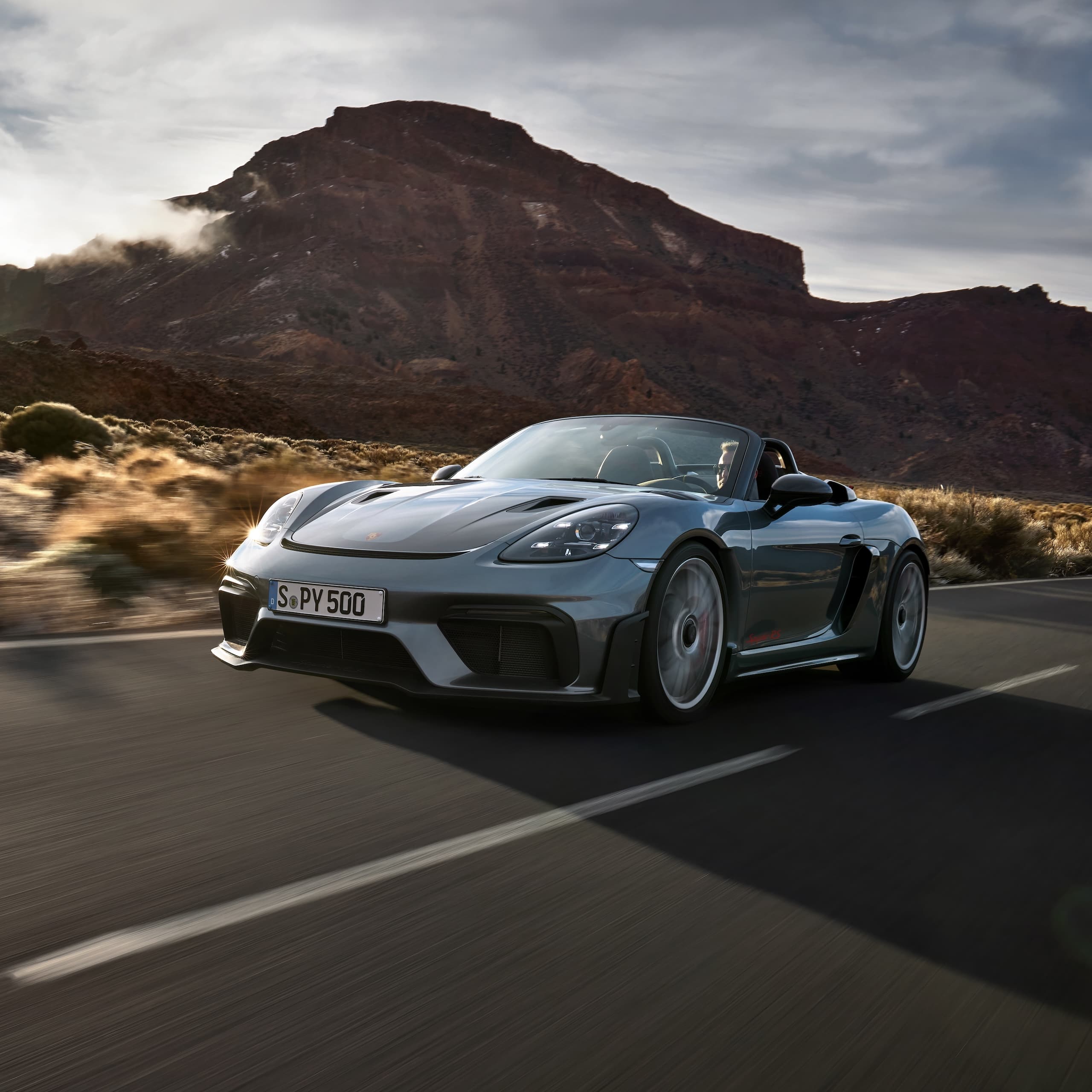 Porsche 718 Spyder RS guida su strada tra formazioni rocciose.