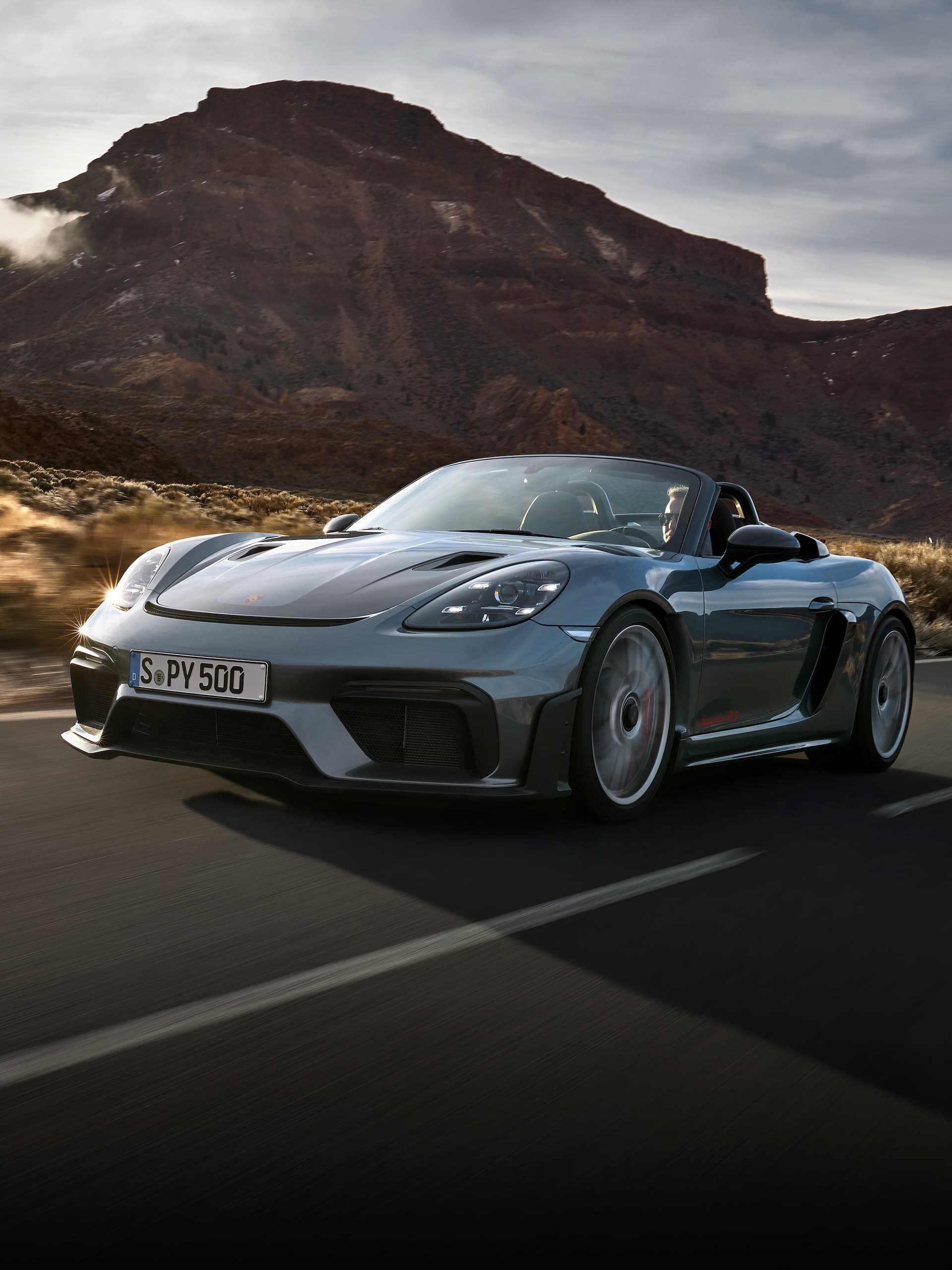 Porsche 718 Spyder RS guida su strada tra formazioni rocciose.