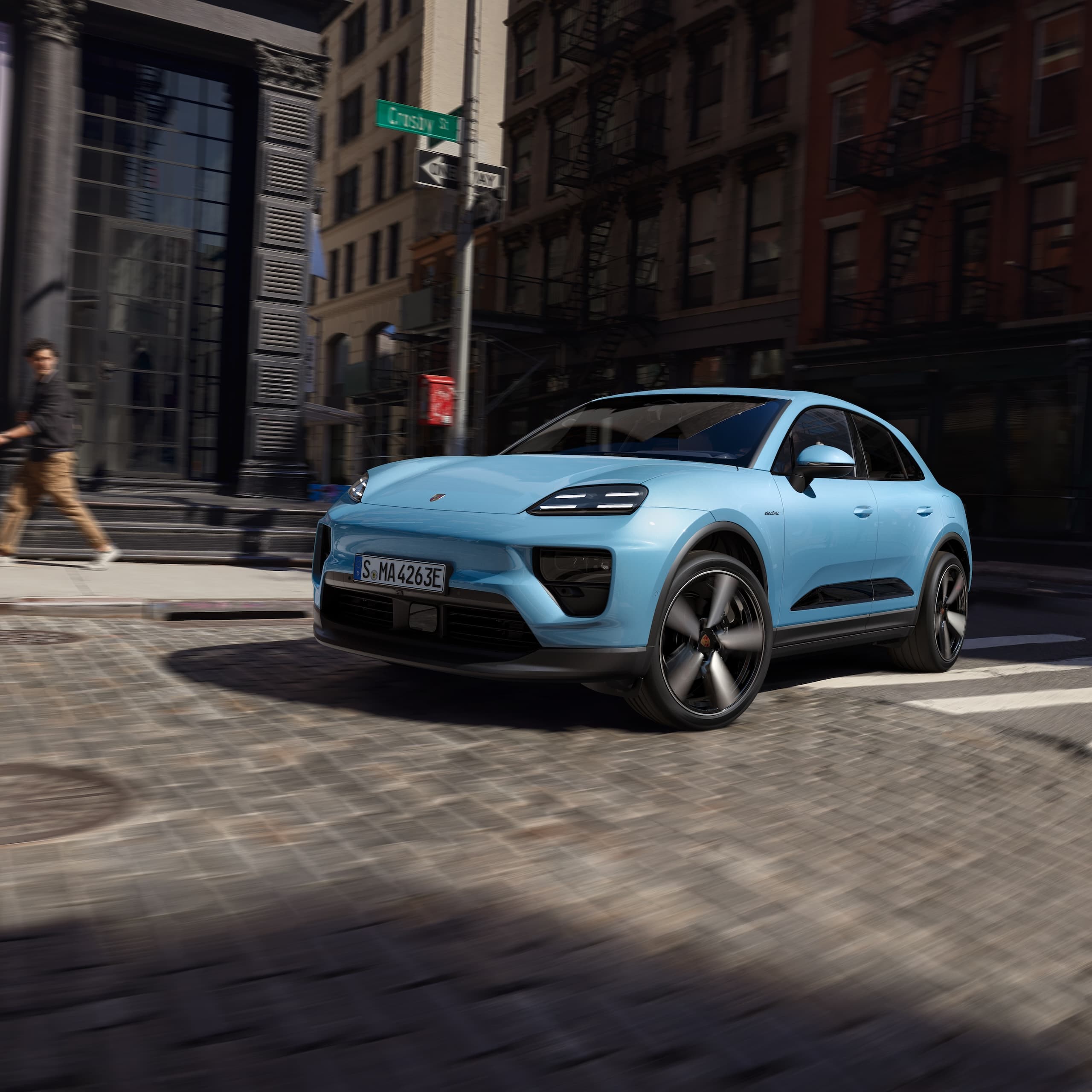 Una Porsche Macan completamente elettrica che guida lungo una strada in uno scenario urbano.